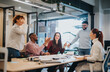 © qunica.com - Multicultural coworkers celebrate successful finished project with joy and positive outcomes in the office. Businesswoman and colleagues smiling and caught up in the victory.