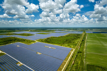 Wall Mural - Aerial view of sustainable electric power plant between agricultural farm fields with solar photovoltaic panels for producing clean electrical energy. Renewable electricity with zero emission concept