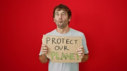 Sticker - Cheerful young activist, confident blond guy making silly fish face. crazy eyes, comical grimace, fun loving! protect our planet banner held high, on isolated red background.