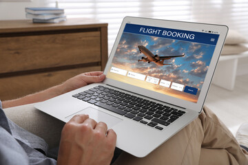 Wall Mural - Man using laptop to book flight at home, closeup