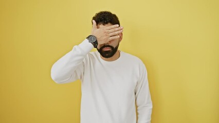 Canvas Print - Distressed young man covering eyes with hand, portraying sad rejection concept, alone against yellow background