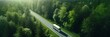 Aerial top view of car and truck driving on highway road in green forest. Sustainable transport. Drone view of hydrogen energy truck and electric vehicle driving on asphalt road through green