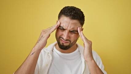 Wall Mural - Stressed-out young arab man standing isolated on yellow, clutching head in sheer migraine agony. suffering etches his handsome face