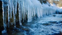 A Frosty Scene Of Icicles Forming Along The Edge Of A Stream, With The Water Flowing Steadily Beneath A Layer Of Ice. Icicles On The Edge Of The River