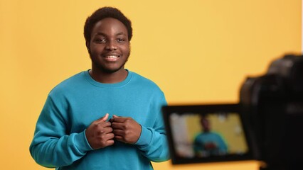 Afro man blogger vlogger talking shooting video use digital camera display isolated orange studio