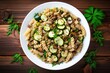 Top view of vegetarian vegetable pasta in a white bowl on a wooden table consisting of fusilli zucchini mushrooms and capers