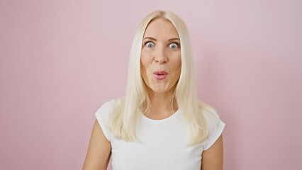 Wall Mural - Shocked and scared! young blonde beauty's face reflects fear and amazement. her astonished expression speaks volumes, standing alone against a pink backdrop.