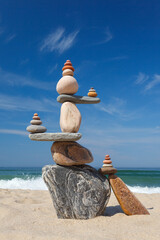 Wall Mural - Big Rock zen Pyramid of balanced stones against the background of the sea and blue sky.