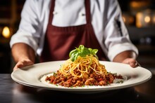Italian Culinary Tradition: Savor The Culinary Artistry As A Chef Showcases A Mouthwatering Plate Of Tagliatelle Al Ragù Alla Bolognese, Epitomizing The Rich Essence Of Bolognese Cuisine.