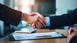 © AspctStyle - Close up image of two business people shaking hands after signing a contract while sitting at the wooden desk