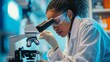 A woman scientist is studying a sample under a microscope.