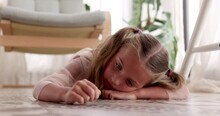 Sad Girl At Floor In Room. Unhappy Face Of Girl. Five Year Old Child Little Girl Is Bored Lying On The Floor Running Her Hand Along. Sad Lazy Kid Preschool Education Concept. Person Loneliness At Home