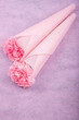 ピンクの紙の上のラッピングしたピンクのカーネーションの花