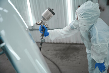 Wall Mural - Specialist paints the hood of a car with white paint