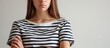 Uncomfortable teenage girl in striped shirt, with skeptical, disapproving face and crossed arms.