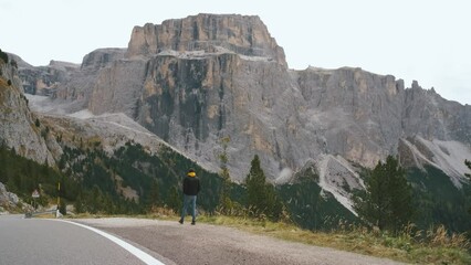 Wall Mural - Beautiful man traveler walks along mountain roads in the Dolomites. Incredibly beautiful views in the Alpine mountains. Route in the Alps mountains in autumn.