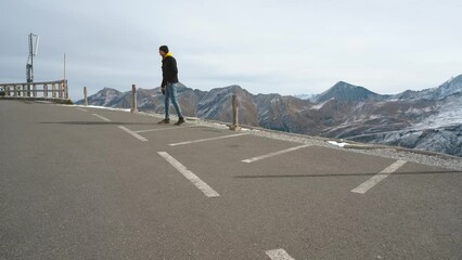 Wall Mural - Man traveler walks along Majestic Grossglockner Mountain Road in Austria, snow covered sharp peaks of the alpine mountains on background. Incredibly beautiful views in the Alpine mountains. Route in