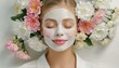Relaxed woman with a cosmetic mask on her face and flowers in the background
