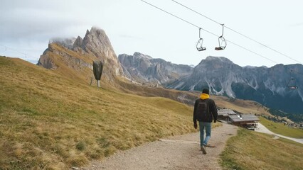 Wall Mural - Man traveler walks to the famous Mount Seceda in the Dolomites. Mountain trail in Alps mountains in autumn or winter. Beautiful alpine mountains in Italy. Seceda, one of the most beautiful mountains