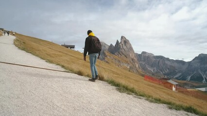 Wall Mural - Man traveler walks to the famous Mount Seceda in the Dolomites. Mountain trail in Alps mountains in autumn or winter. Beautiful alpine mountains in Italy. Seceda, one of the most beautiful mountains