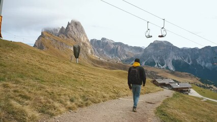 Wall Mural - Man traveler walks to the famous Mount Seceda in the Dolomites. Mountain trail in Alps mountains in autumn or winter. Beautiful alpine mountains in Italy. Seceda, one of the most beautiful mountains