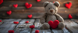Fototapeta Pokój dzieciecy - A beloved teddy bear adorned with red hearts sits atop a wooden shelf, bringing warmth and comfort to any indoor space with its plush fabric and timeless charm