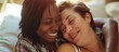 Joyful lesbian woman embracing expectant multiracial spouse at home, their faces beaming.