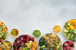 Preparing fresh vegetables in summer for winter, various frozen vegetables and berries in plates on a gray background, top view, copy space