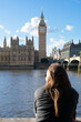 Female tourist admiring Big Ben Clock tower from across the Thames river. UK, London