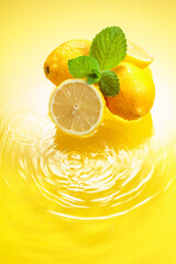 Wall Mural - Juicy lemons with mint on a yellow background with water splashes.