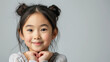 © Andrii - Portrait of a happy asian girl on a gray background.