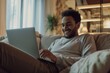 © Nuttakarn - Smiling Man Using Laptop in Cozy Living Room