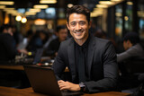 Fototapeta Londyn - A confident, successful Asian businessman with a laptop, exuding positivity and professionalism in an office.