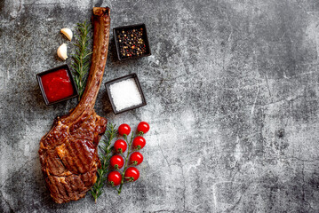 Wall Mural - Grilled Tomahawk steak on stone background with copy space for text

