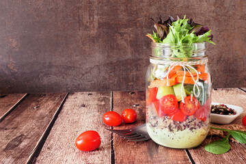 Poster - Healthy, homemade mason jar salad with vegetables and quinoa.  Side view table scene on dark background.