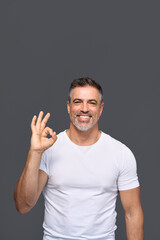 Wall Mural - Happy fit sporty older man coach, middle aged sportsman personal trainer wearing white t-shirt showing ok gesture standing isolated on gray background advertising gym membership. Vertical.