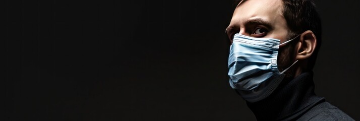 Wall Mural - young man in medical mask on black background with copy space. Medical Mask. Pandemic Concept with copy space. Healthcare Concept. Epidemic Concept. Copy Space., panoramic shot