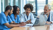 © MP Studio - Diverse group of medical professionals, including doctors and nurses, engaged in a discussion around a laptop