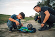 © Zamrznuti tonovi - Son and dad checking their overturned and broken toy car outdoors.