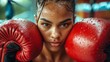 Female boxer with a determined stare, red boxing gloves on, focused and ready. Concept of boxing, strength, female empowerment in sports, and athletic focus.