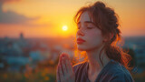 Fototapeta  - A believing girl prays in a field at sunrise