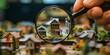 © ParinApril - Hand using a magnifying glass to inspect miniature houses