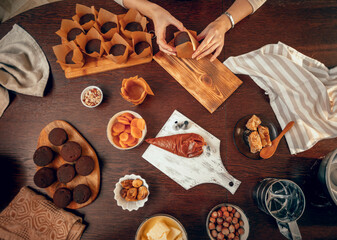 Wall Mural - A young woman packs cupcakes in kraft paper, top view. birthday cupcakes. small business. chef bakery bakes cakes and pies in the kitchen