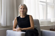 © fizkes - Portrait of beautiful middle-aged woman smile look at camera. Beautiful mature female relaxing on cozy armchair in living room staring at cam spend carefree weekend alone at own or rented apartment