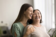 © fizkes - Joyful adult child woman hugging happy mom from behind, holding shoulders, talking, smiling, laughing, enjoying closeness, embracing mother with love, affection, care, gratitude
