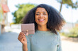 Young African American woman holding a wallet at outdoors with happy expression