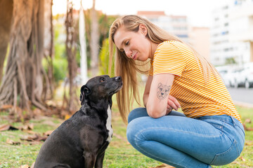 Wall Mural - Young blonde woman with her adorable black dog at outdoors