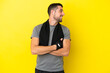 Leinwandbild Motiv Young sport caucasian man isolated on yellow background with arms crossed and happy