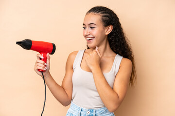 Wall Mural - Young woman holding a hairdryer isolated on beige background celebrating a victory