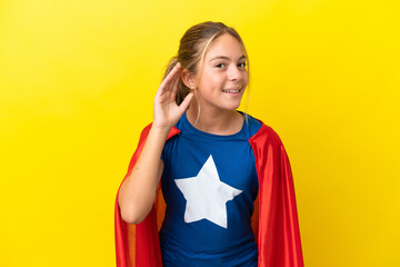 Wall Mural - Super Hero little girl isolated on yellow background listening to something by putting hand on the ear